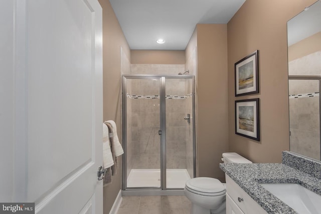 bathroom featuring tile patterned flooring, a shower with door, vanity, and toilet