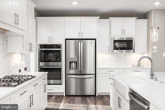 kitchen featuring decorative backsplash, dark hardwood / wood-style floors, hanging light fixtures, white cabinetry, and stainless steel appliances