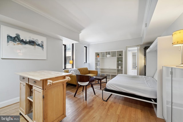 bedroom with light wood-style floors, baseboards, and crown molding