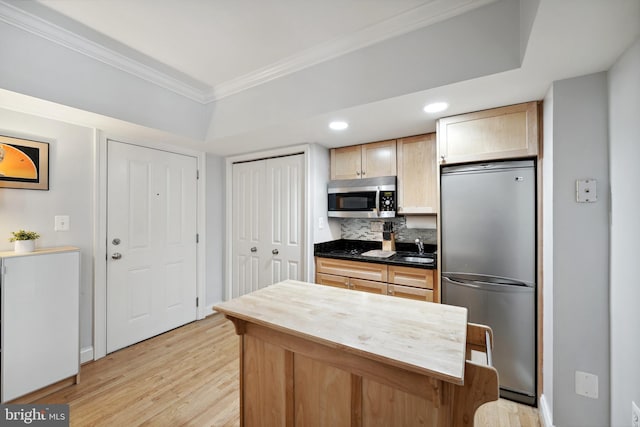 kitchen featuring light wood finished floors, stainless steel appliances, crown molding, light brown cabinets, and a sink