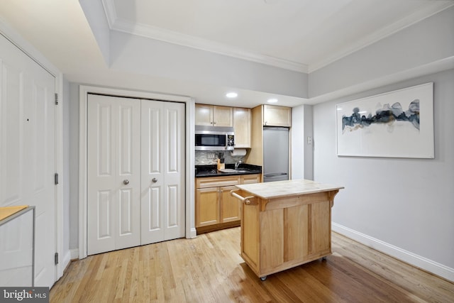 kitchen featuring a center island, stainless steel appliances, dark countertops, ornamental molding, and light brown cabinets