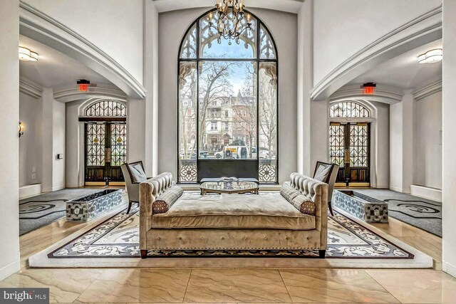 sitting room featuring light tile patterned floors, an inviting chandelier, a high ceiling, and french doors