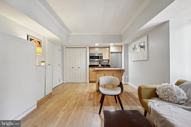 living area with ornamental molding, light wood finished floors, and baseboards