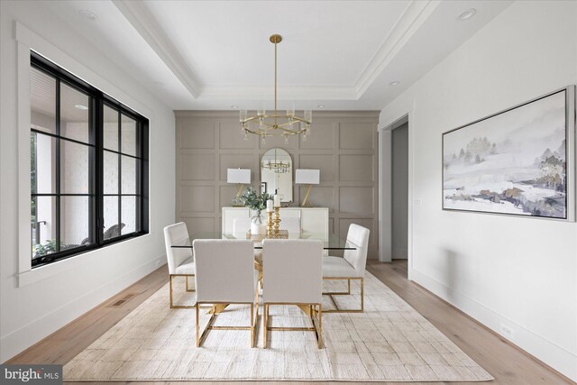 dining area with light hardwood / wood-style floors, a chandelier, and a tray ceiling