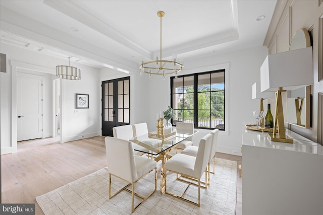 dining area featuring light hardwood / wood-style floors, a raised ceiling, a notable chandelier, and french doors