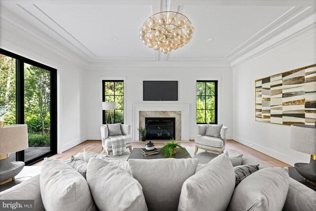 living room with a wealth of natural light, a notable chandelier, light wood-type flooring, and a fireplace