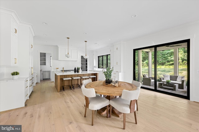 dining room with sink, light hardwood / wood-style flooring, and ornamental molding