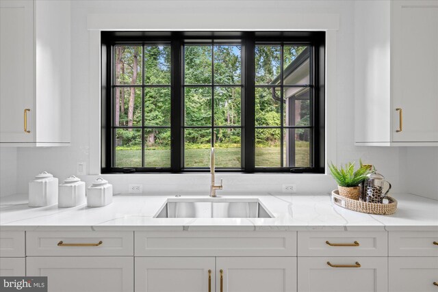 kitchen featuring plenty of natural light, light stone countertops, and white cabinets