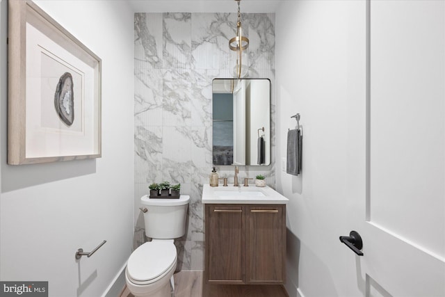 bathroom featuring tile walls, vanity, and toilet