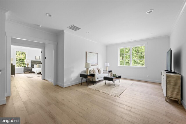 living area featuring a wealth of natural light, light hardwood / wood-style floors, and crown molding