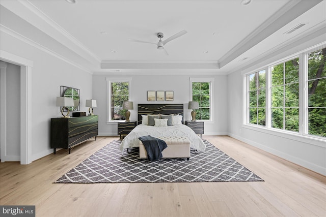 bedroom featuring multiple windows, hardwood / wood-style flooring, a tray ceiling, and ceiling fan