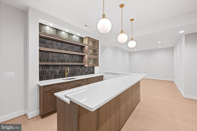 bar with sink, decorative light fixtures, and light hardwood / wood-style flooring