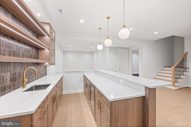 kitchen featuring decorative backsplash, sink, light wood-type flooring, a kitchen island, and hanging light fixtures