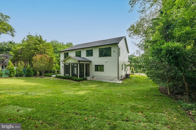 rear view of property with a sunroom, cooling unit, and a lawn