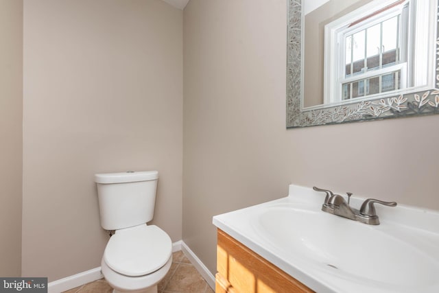 bathroom with toilet, tile patterned floors, baseboards, and vanity