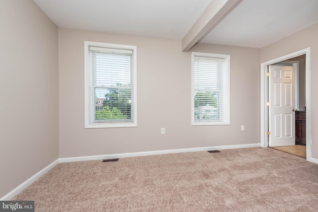 carpeted empty room featuring visible vents, baseboards, and beam ceiling