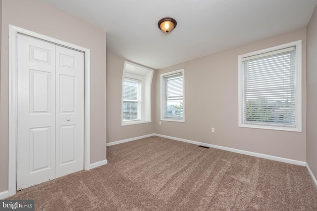 unfurnished bedroom with carpet floors, a closet, visible vents, and baseboards