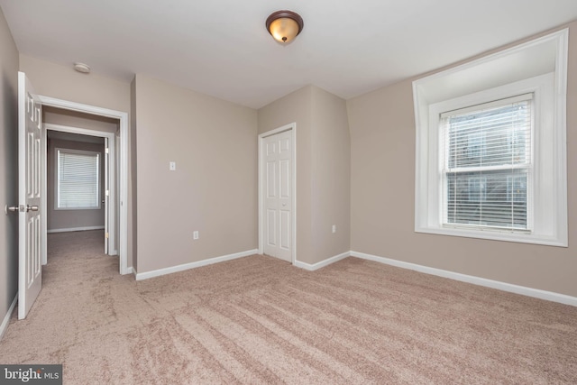 unfurnished bedroom with baseboards, a closet, and light colored carpet