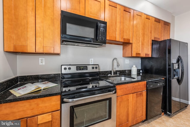 kitchen featuring a sink, black appliances, brown cabinetry, and dark stone countertops