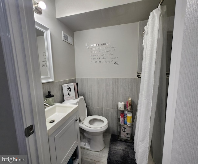 bathroom with a shower with curtain, vanity, tile walls, and toilet