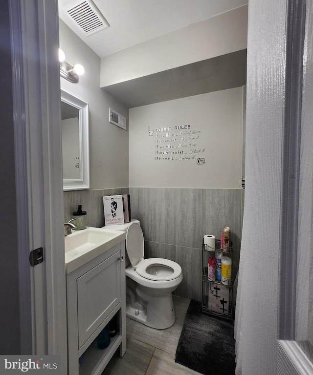 bathroom with tile walls, toilet, and vanity