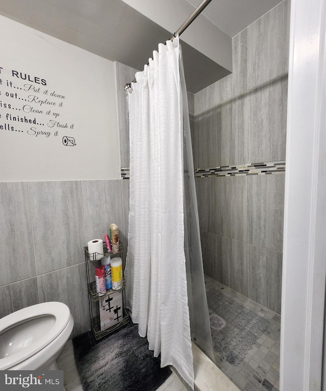 bathroom featuring a shower with shower curtain, toilet, and tile walls