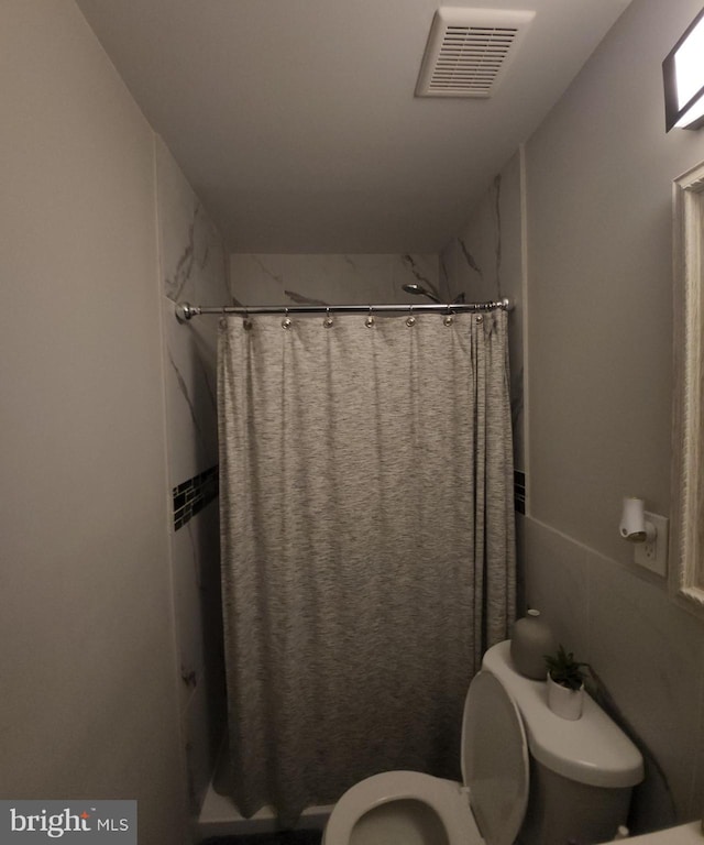 bathroom with a shower with curtain and toilet