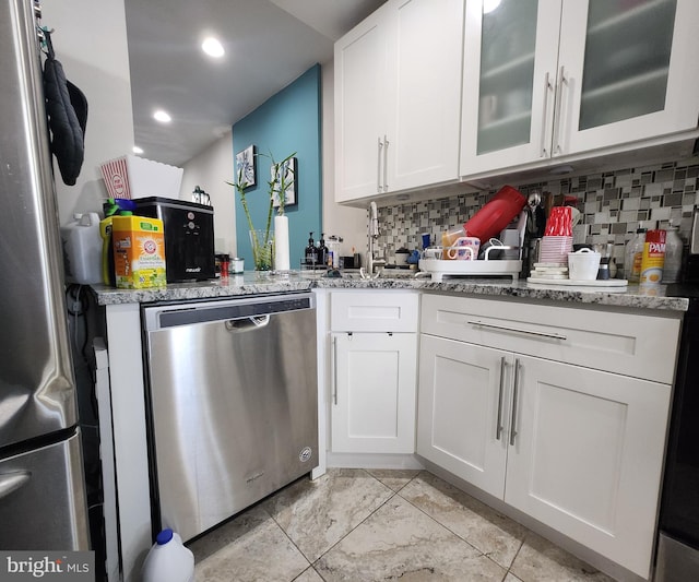 kitchen with white cabinets, appliances with stainless steel finishes, decorative backsplash, and light stone countertops