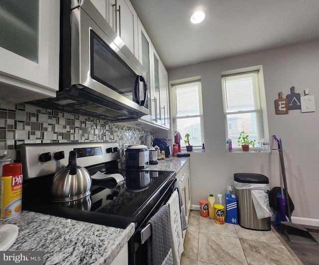 kitchen with tasteful backsplash, light stone counters, stainless steel appliances, and white cabinets