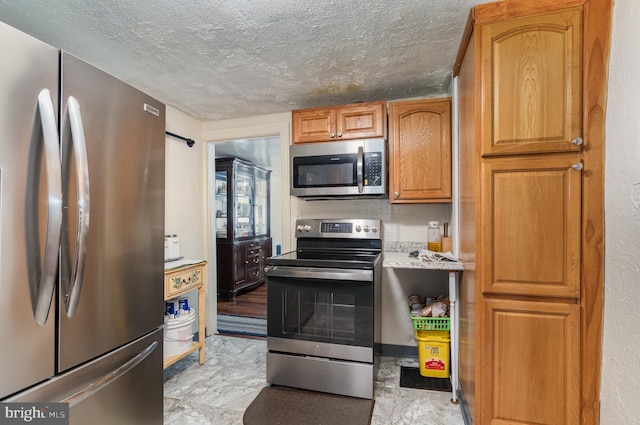 kitchen with a textured ceiling, appliances with stainless steel finishes, and light tile patterned floors