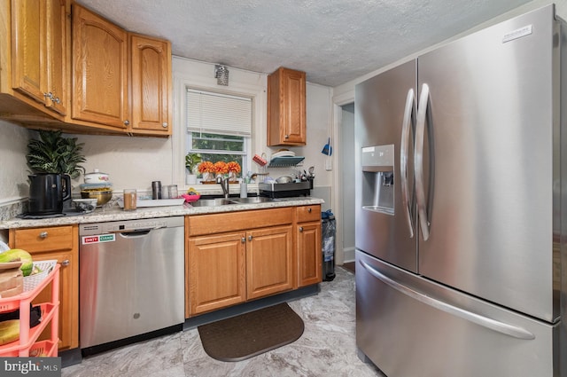 kitchen featuring light tile patterned floors, appliances with stainless steel finishes, sink, and a textured ceiling