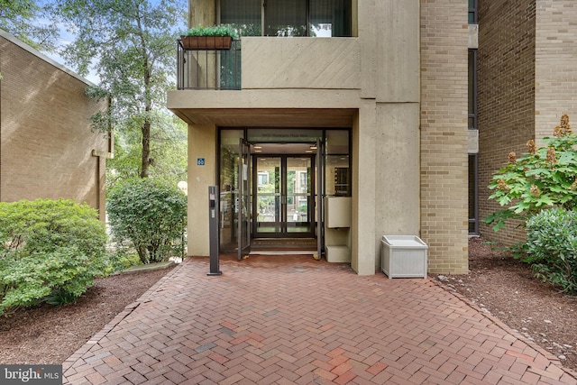 view of exterior entry with a balcony and french doors