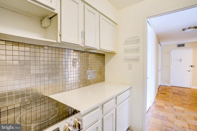 kitchen featuring backsplash, white cabinetry, light parquet floors, and stove