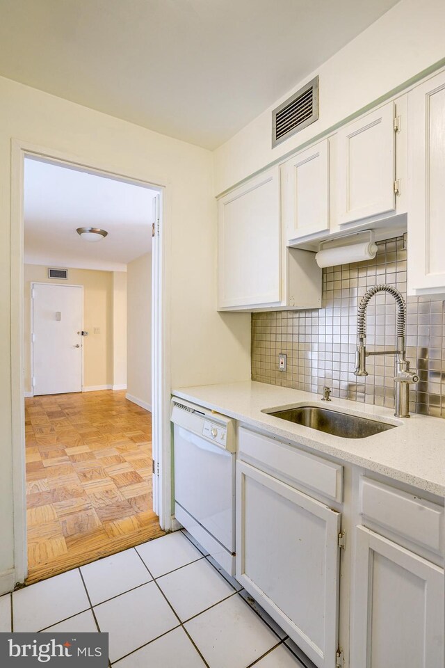 kitchen with backsplash, dishwasher, light tile patterned flooring, and white cabinets