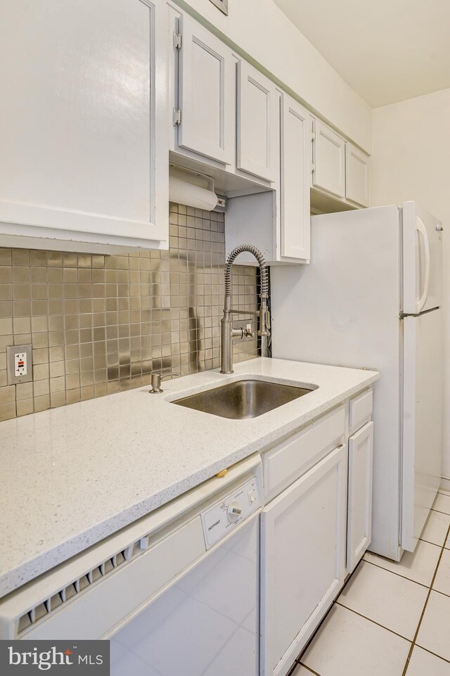 kitchen featuring backsplash, white cabinets, sink, light tile patterned flooring, and white appliances