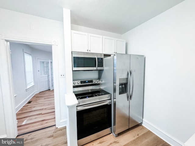 kitchen featuring light wood-type flooring, appliances with stainless steel finishes, and white cabinetry