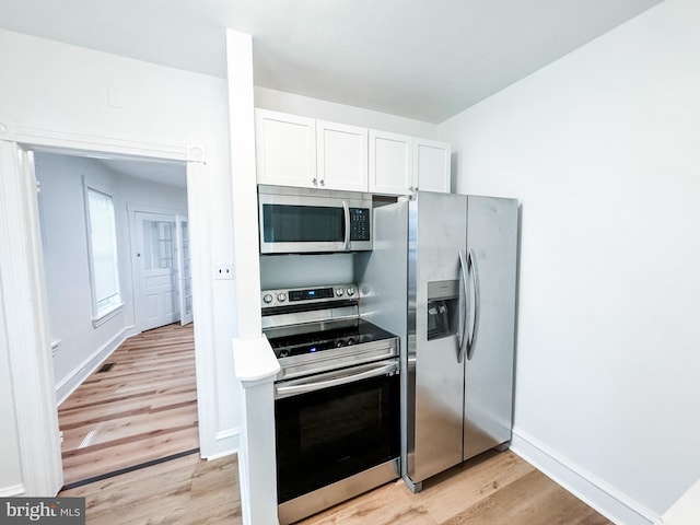 kitchen featuring baseboards, white cabinets, stainless steel appliances, light countertops, and light wood-type flooring