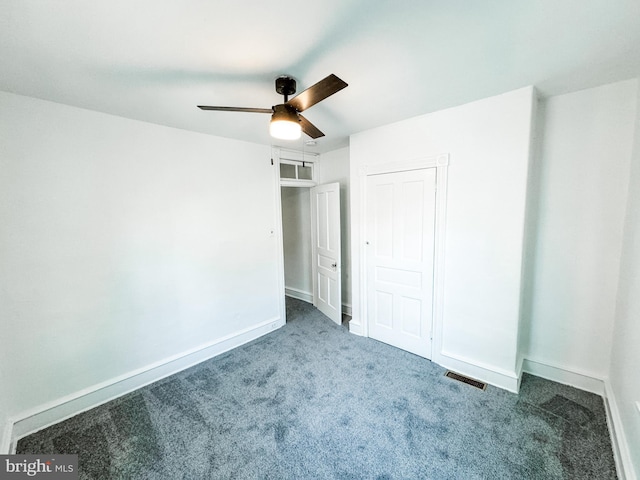 unfurnished bedroom featuring visible vents, dark carpet, baseboards, and ceiling fan