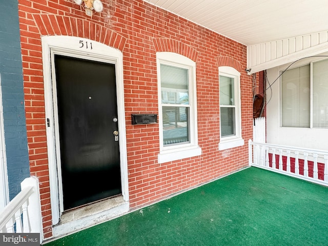 entrance to property featuring brick siding and a porch