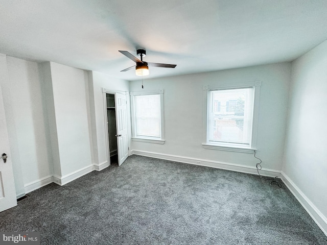 unfurnished bedroom featuring ceiling fan, dark colored carpet, and multiple windows