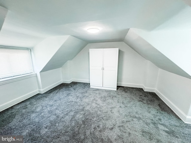 bonus room with lofted ceiling, baseboards, and dark colored carpet