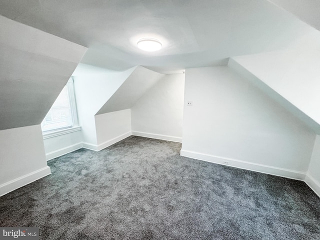 additional living space featuring vaulted ceiling and dark carpet