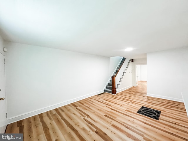 basement featuring light wood-style flooring, visible vents, stairway, and baseboards