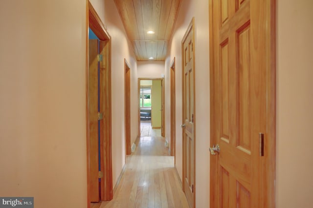 corridor with light wood-type flooring and wooden ceiling