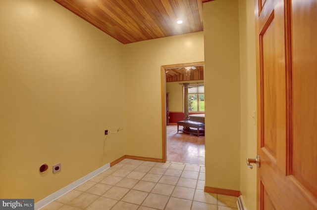 corridor with baseboard heating, wooden ceiling, and light tile patterned floors