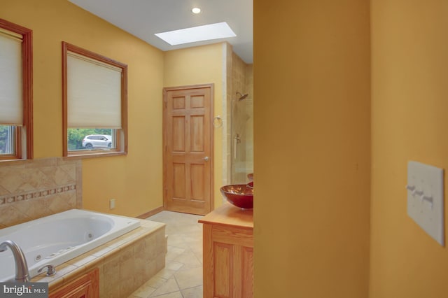 bathroom with shower with separate bathtub, tile patterned flooring, vanity, and a skylight