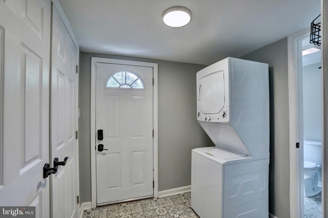 clothes washing area with stacked washer / drying machine, laundry area, and baseboards