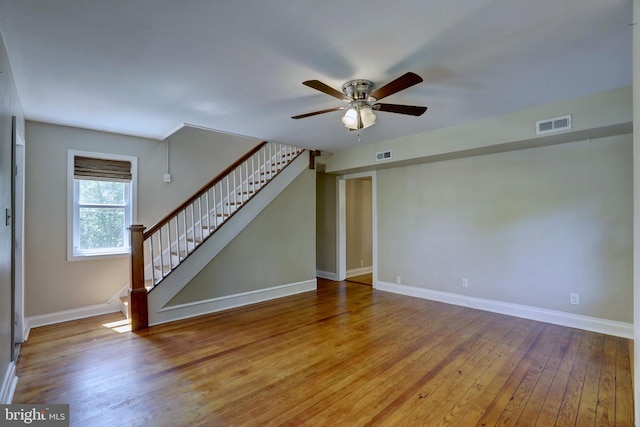 unfurnished room featuring visible vents, stairway, baseboards, and wood finished floors