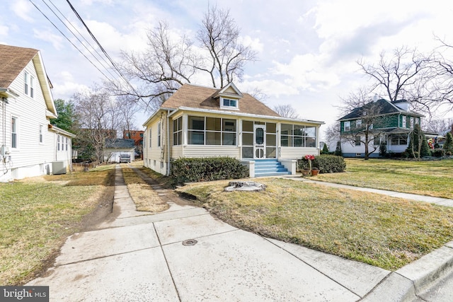 bungalow-style home with a front yard, cooling unit, and a sunroom