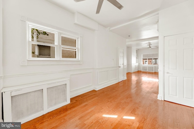 spare room featuring light wood-type flooring, radiator heating unit, and ceiling fan